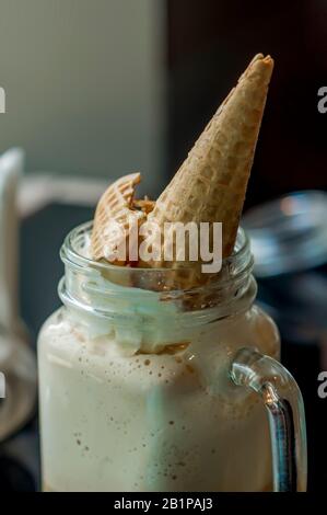 Nahaufnahme von kaltem Kaffee mit Schlagsahne und Waffelkonus Stockfoto