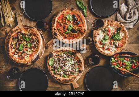 Verschiedene Arten von italienischer Pizza, frischem Salat und Rotwein Stockfoto