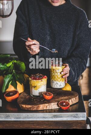 Frau, die Müsli mit Mango-Smoothie, Granola und Beeren isst Stockfoto