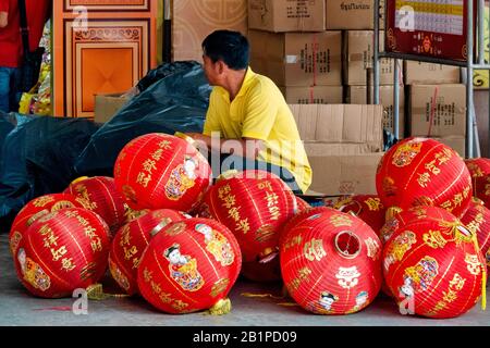 Ein Mann, der im Wat Mangkon Kamalawat Tempel in Chinatown, Bangkok, Thailand, Laternen für das chinesische Neujahr aufstellt Stockfoto