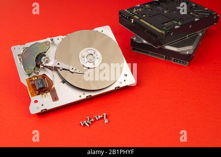 HDD - Festplatte. Festplattenreparaturkonzept, Computerindustrie. Demontieren Sie die Festplatte aus dem 3,5'-SATA-Computer auf rotem, üppigem Lavafelgrund Stockfoto
