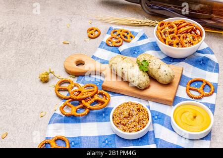 Oktoberfest-Set. Dunkles Bier, Weisswurst, Brezeln, Senf, Ährchen Getreide, Hopfen. Traditionelle deutsche Küche, Festessen. Becher, LeinenServiette, ston Stockfoto