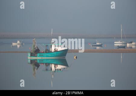 Fischerboote vor Anker im Morgennebel an einer Flussmünde Stockfoto