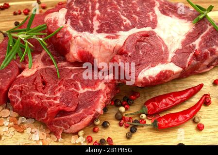Rohes Rindfleisch Steaks auf Holzbrettblick von oben. Frisches Steak mit Gewürzen bereit zum Kochen. Nahaufnahme Stockfoto