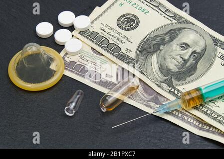 Geld und Pillen mit Drogen und einer Spritze auf Schwarz Stockfoto