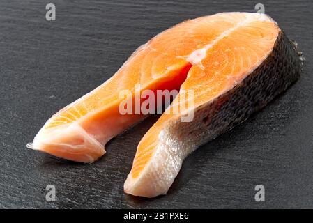 Rohes Lachssteak auf schwarzem Stein, zum Kochen vorbereitet. Nahaufnahme Stockfoto