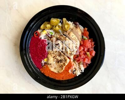 Nehmen Sie Die jamaikanische Food Bowl mit Hühnchen, roten Nierenbohnen, Rübensoße, Basmati-Reis-Pilaf, Avocado Guacamole, Jalapeno Pepper und Coconut Milk in Pl Stockfoto