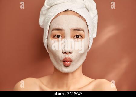 Junge schöne Frau mit Lehm Gesichtsmaske. Spa Behandlung, Selbsthilfe und gesunde Haut Stockfoto