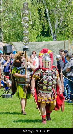 Reenactors, die den Kommandanten des römischen Lagers und einen Signifer vertreten, der einen Standard mit Auszeichnungen auf dem römischen Festival von Carnuntum, Österreich, trägt Stockfoto