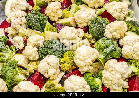 Verschiedene frische Gemüse auf einem Backblech Blumenkohl, Brokkoli, Rüben, Zucchini. Meersalz, gemahlener schwarzer Pfeffer, Olivenöl. Gesundes Lebensmittelkonzept, Klo Stockfoto