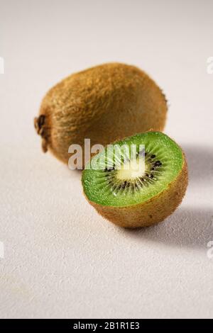 Kiwi-Früchte halbiert auf lebendem, einfarbig weißem Hintergrund, Makro-Nahaufnahme Stockfoto