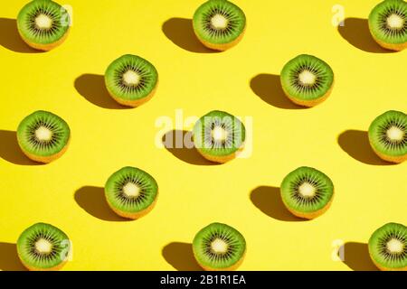 Kiwi Fruits Elemente Muster Layout, minimalistisches abstraktes Design flaches Lay, gesundes Essen, Winkelansicht, leuchtend gelber Hintergrund Stockfoto