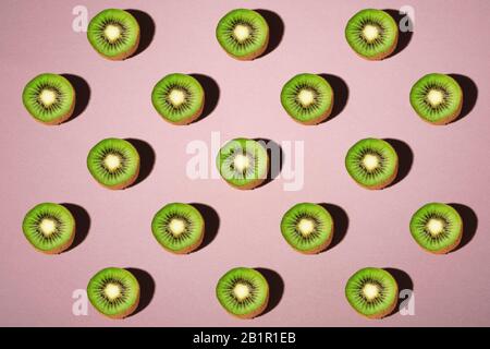 Kiwi Fruits Elemente Muster Layout, minimalistisches abstraktes Design flaches Lay, gesundes Essen, Winkelansicht, pastellrosa Hintergrund Stockfoto