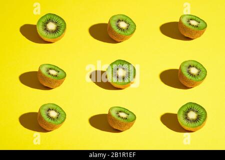 Kiwi Fruits Elemente Muster Layout, minimalistisches abstraktes Design flaches Lay, gesundes Essen, Winkelansicht, leuchtend gelber Hintergrund Stockfoto