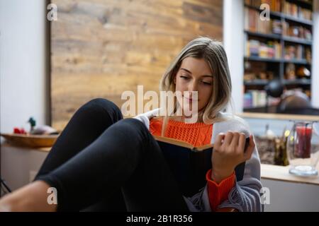 Junge Frau, die ein Buchheim liest Stockfoto