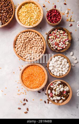 Linsen, Chikpea und Bohnen in verschiedenen Schüsseln auf weißem Steintisch Draufsicht. Stockfoto