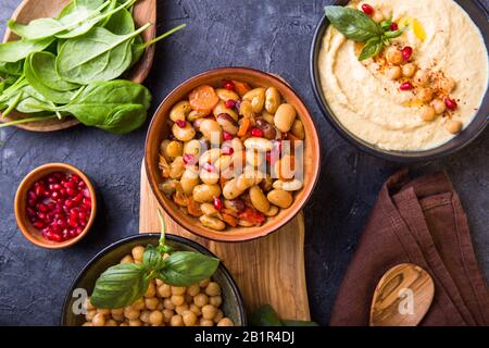 Gekochte Nierenbohnen, weiße Bohnen, Kichererbsen und hausgemachter Hummus auf einem Teller, Steinhintergrund. Blick auf den Yop Stockfoto