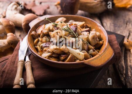 Gebratene Waldpilze, Boletus, Zwiebeln. Rustikales Gericht in einer Bratpfanne, vegetarische Herbstkost im Vordergrund Stockfoto