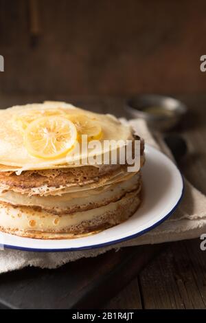 Honig- oder Ahorn-Sirup, der über Crepes gießt. Nahansicht des Stapels dünner Pfannkuchen, blini Stockfoto