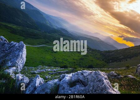 Strahlen, die bei Sonnenuntergang eine Decke von Wolken in den hohen Bergen überqueren Stockfoto