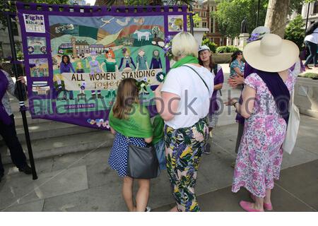 Frauen versammeln sich um ein Banner, das für die 100-jährige Parade zum Feiern des Frauenwahlrechts gemacht wurde Stockfoto