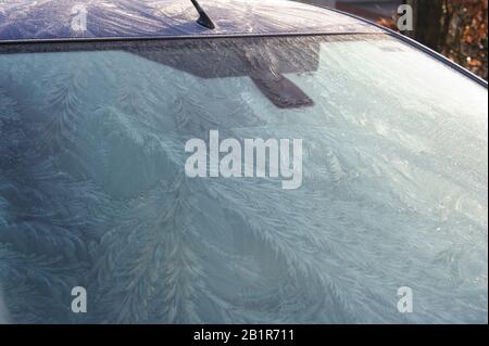 An der Windschutzscheibe eines Wagens bildeten sich Eis- und Frostmuster Stockfoto