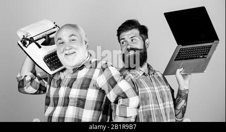 Jugend vs Alter. business Ansatz. Vater und Sohn. Technologie Entwicklung und Verbesserung. retro Schreibmaschine laptop vs. Technologie generation kämpfen. Das moderne Leben. Zwei bärtigen Männern. Vintage Schreibmaschine. Stockfoto