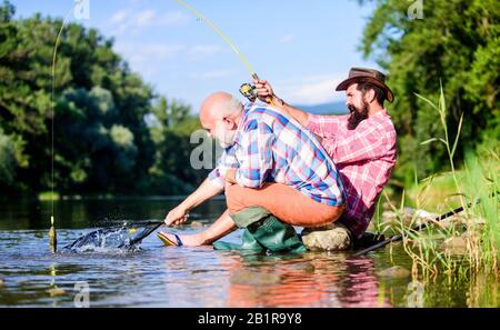 Männer sitzen am Flussufer mit Angelausrüstung. Wildverbrechen und Angelschein. Wilderer angeln. Schwarzmarktkaviar. Illegaler Jagdkaviar. Extrahiert Eier aus Stör gefangenen Fluss. Falle für Fisch. Stockfoto
