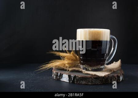 Russisches traditionelles Getränk fermentierter Kvass aus Roggenbrot im speziellen Halbliter-Becher auf dunklem Hintergrund. Kopierbereich. Stockfoto