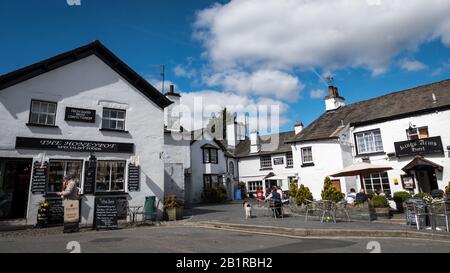 Hawkshead, Cumbria, England. Das beliebte Dorf im Herzen des Lake District mit Touristen vor einem kleinen Geschäft und Hotel. Stockfoto