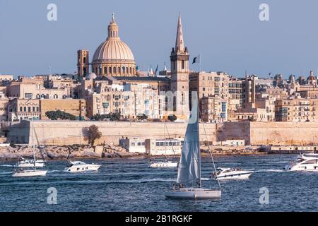 Weiße Yacht und Boote im Hafen von Valletta, Unserer Lieben Frau von der Kirche Mount Carmel und der anglikanischen Pro-Kathedrale St. Paul im Hintergrund, Valletta, Malta Stockfoto