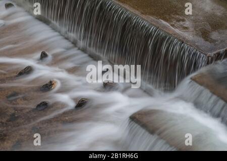 Wasser fließt über ein Stepper Wehr in Laxey auf der Isle of man, Großbritannien Stockfoto