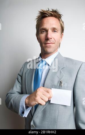 Seriöser Büroangestellter, der seinen leeren Namensschild hält Stockfoto