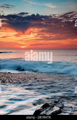 Eingehende Flut mit der Sonne über dem Wasser untergeht und projiziert ein wunderbares Leuchten, romantisch, Horizont, dramatischen Himmel, Abend, Schein, Himmel, Küste, Küste Stockfoto