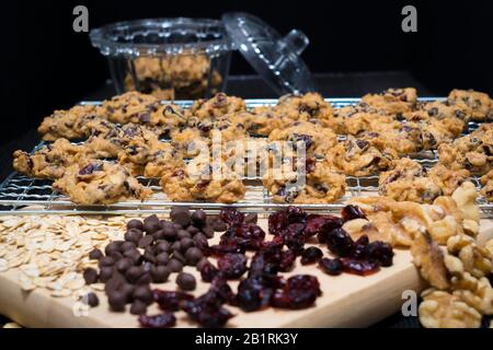 Verschiedene frisch gebackene Plätzchen und Süßwaren, die auf Kabelgestellen und einem Küchentisch in einer Bäckerei ausgestellt sind Stockfoto
