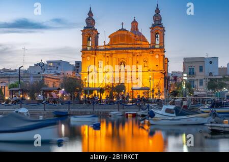 Hafen von Valletta mit Yachten und Fischerbooten, Msida Parish Church of Saint Joseph bei Sonnenuntergang, Malta Stockfoto