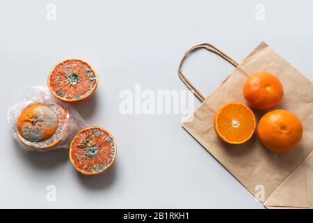 Vergleich der Lagerung von orangefarbenen Produkten in Plastiktüten und Papiertüten. Falsche Lagerung. Stockfoto