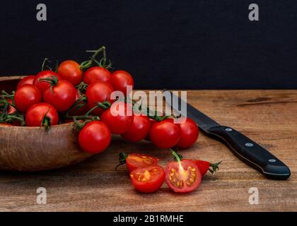 Frisch tomatillos auf schwarzem Hintergrund von der Seite betrachtet, Frisch ganz und geschnitten (halbiert) rot tomatillos auf schwarzem Hintergrund von oben betrachtet - Essen ST Stockfoto