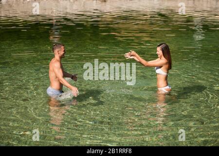 Aktives junges Paar spielt an einem heißen Sommermorgen im Flachwasser Stockfoto