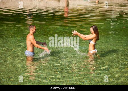 Aktives junges Paar spielt an einem heißen Sommermorgen im Flachwasser Stockfoto