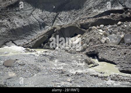 Der Schnack eines Gletschers, der Morraine trägt, wobei große Eisblöcke abgebrochen wurden und ein Schmelzwasserfluss ausströmt Stockfoto