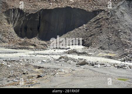 Der Schnack eines Gletschers, der Morraine trägt, wobei große Eisblöcke abgebrochen wurden und ein Schmelzwasserfluss ausströmt Stockfoto