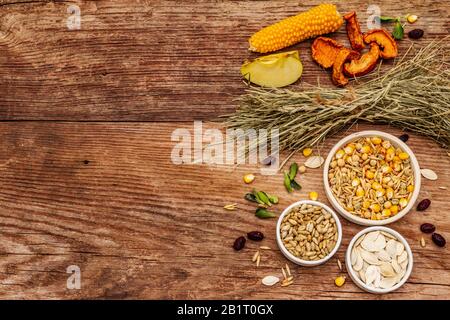 Ausgewogene Ernährung für heimische Nagetiere. Verschiedene Mischung aus Getreide und Samen, trockenen Kräutern und frischen Früchten. Alter Holzhintergrund, Draufsicht Stockfoto