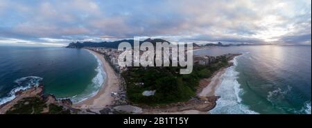 Arpoador-Felsen in Rio de Janeiro mit Ipanema und Copacabana-Strand auf beiden Seiten und breiterem Stadtbild im Hintergrund vor einem übergiebelten Himmel Stockfoto