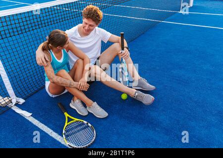 Foto eines positiven jungen Tennisspielers zwei Frauen und Männer im Freien im Gespräch miteinander. Stockfoto