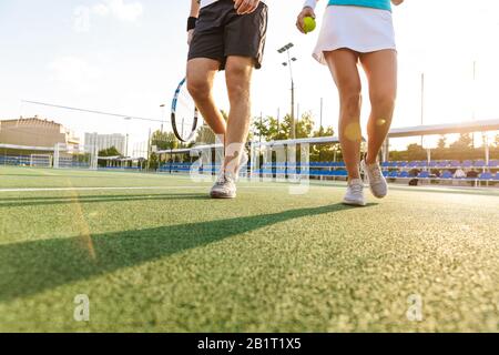 Gekipptes Bild von kaukasischer Frau und Mann in Sportbekleidung, die Schläger hält, während sie auf dem Platz im Freien Tennis spielen Stockfoto