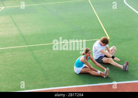 Attraktives, gesundes Fitness-Paar, das Dehnübungen im Stadion macht Stockfoto