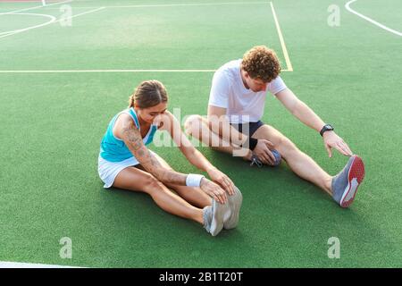 Attraktives, gesundes Fitness-Paar, das Dehnübungen im Stadion macht Stockfoto
