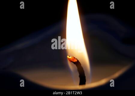 Die Nahaufnahmen einer brennenden Kerze, die auf dem schwarzen Hintergrund isoliert ist Stockfoto