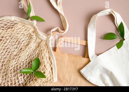 Verschiedene umweltverträgliche Beutel. Wiederverwendbare Netztasche, Papiertasche und Baumwolltasche auf braunem Hintergrund. Stockfoto